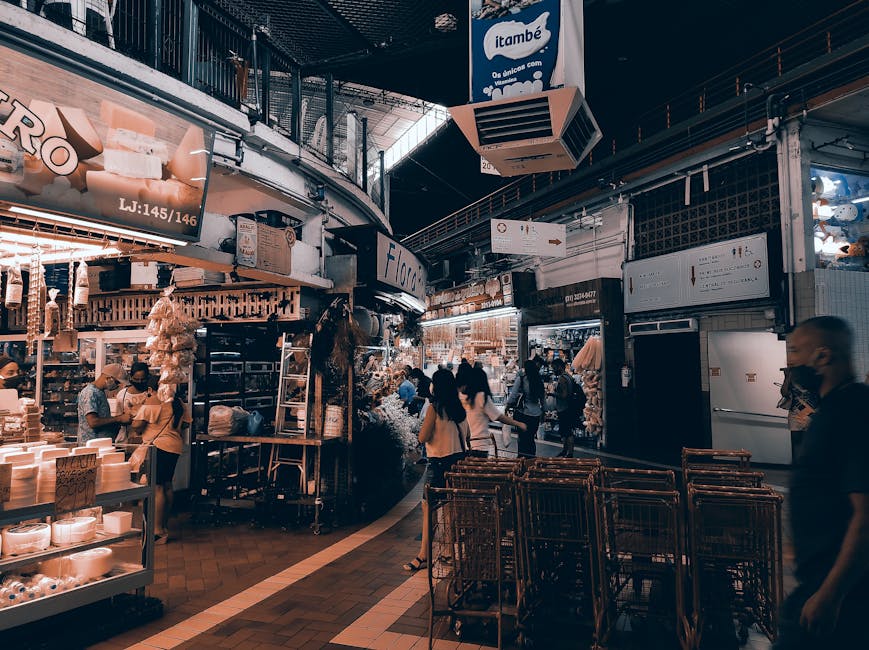 Inside a retail store, several cardboard boxes of varying sizes are stacked near the checkout area illuminated by natural light, casting shadows on the packaging. Some boxes are sealed with packing ta